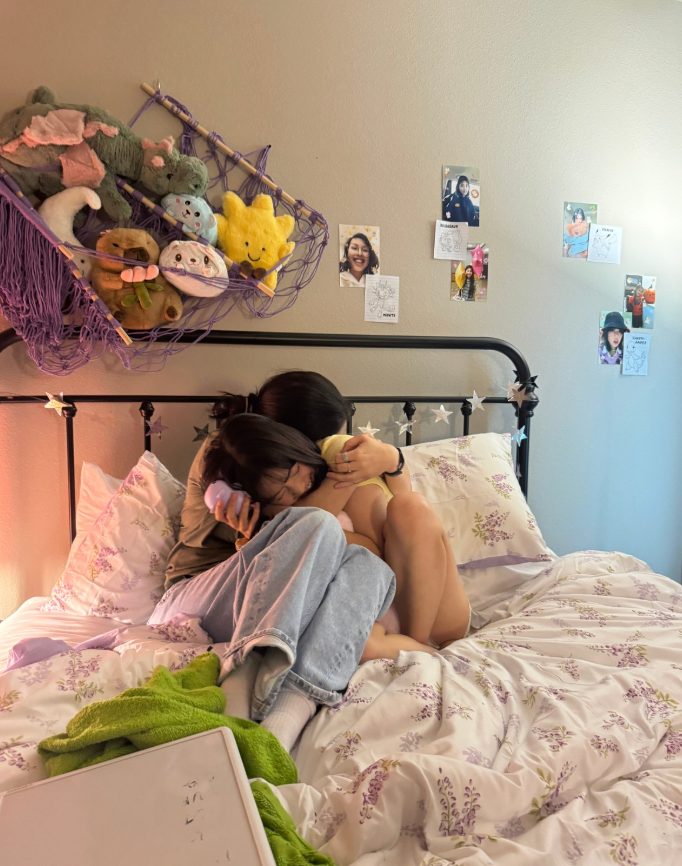 Two people sitting together on a bed, one comforting the other
